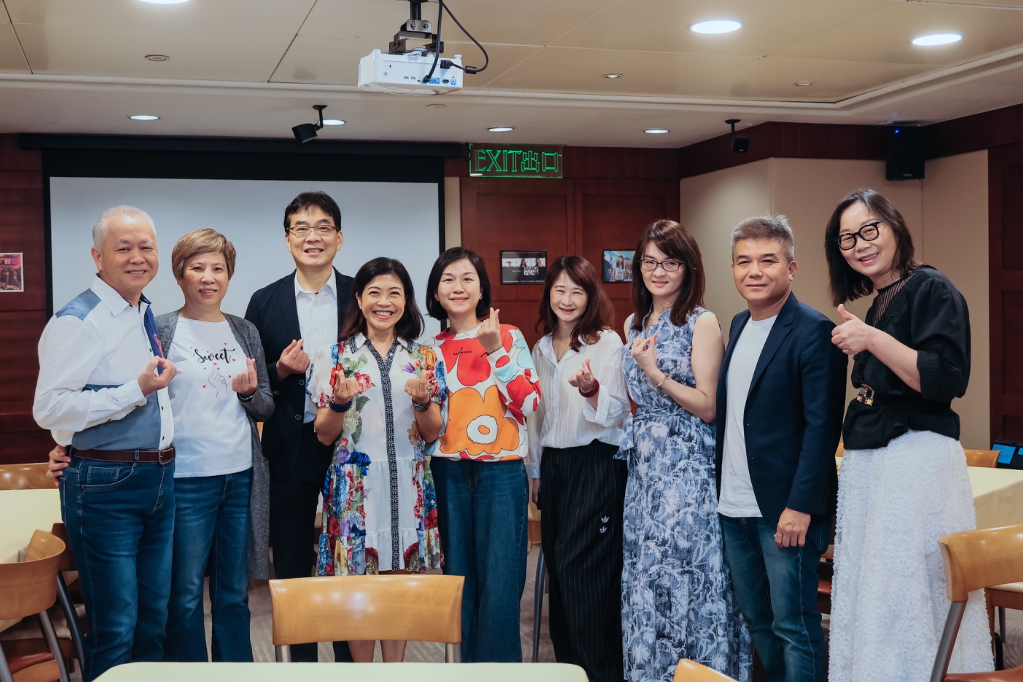 Guests at the opening gathering posing together with finger-heart gestures